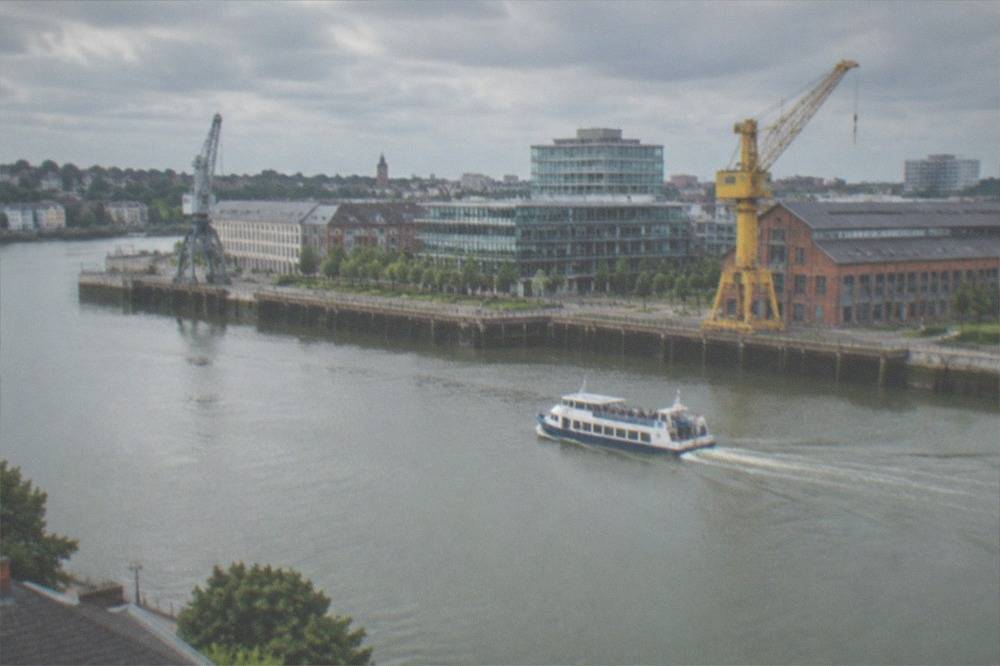 A small passenger ferry crossing the Loire between the Île de Nantes and the south bank houses of Trentemoult