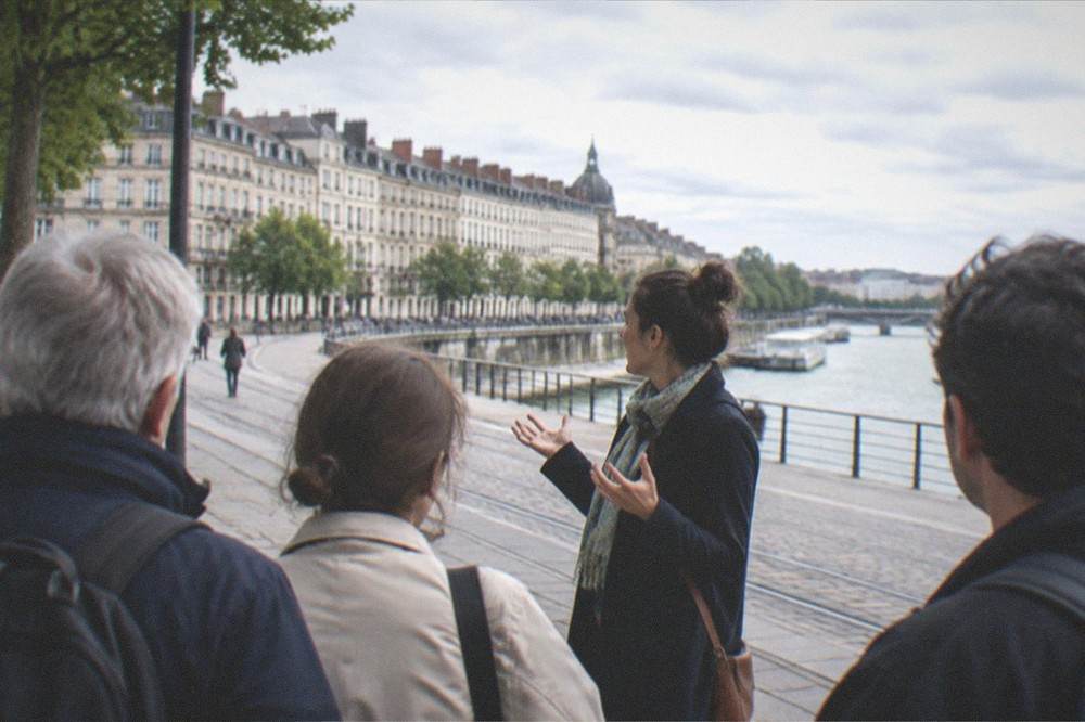 A guide speaking with a small group of visitors on a Nantes street near the riverside quay