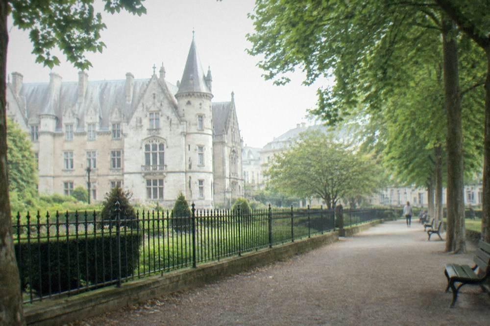 A quiet gravel path lined with trees and benches in the garden beside the Musee Dobrée