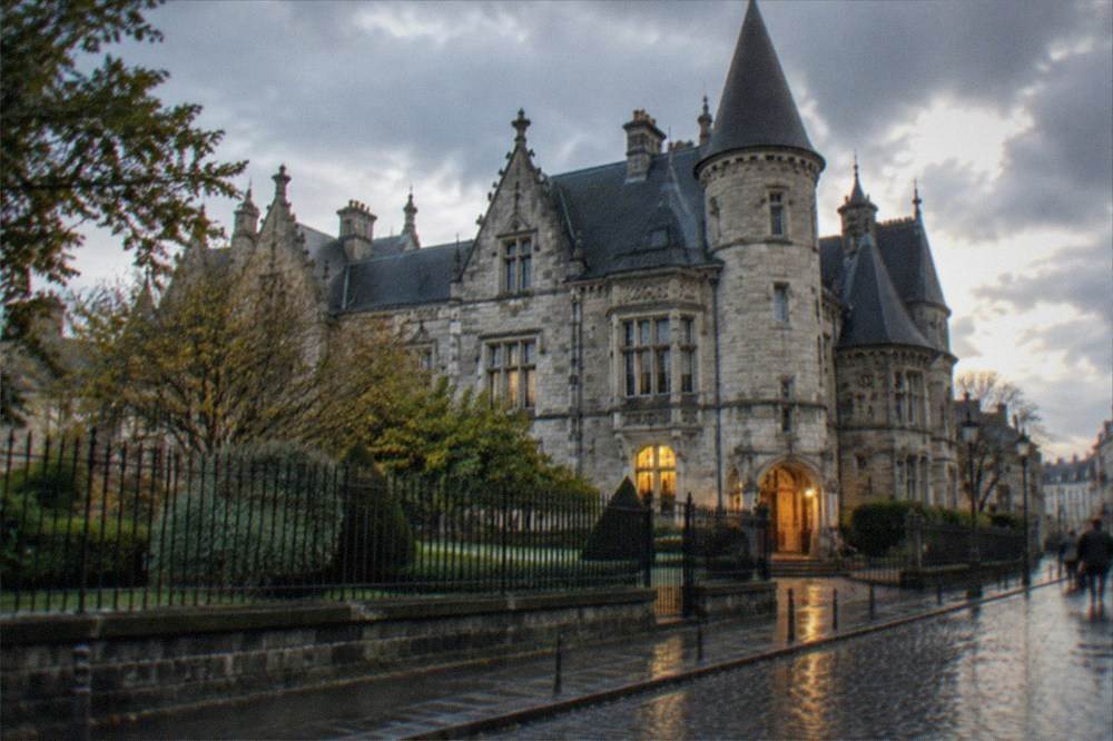 Rain-slicked cobbled street outside the Musee Dobrée with the museum entrance glowing warmly in the evening