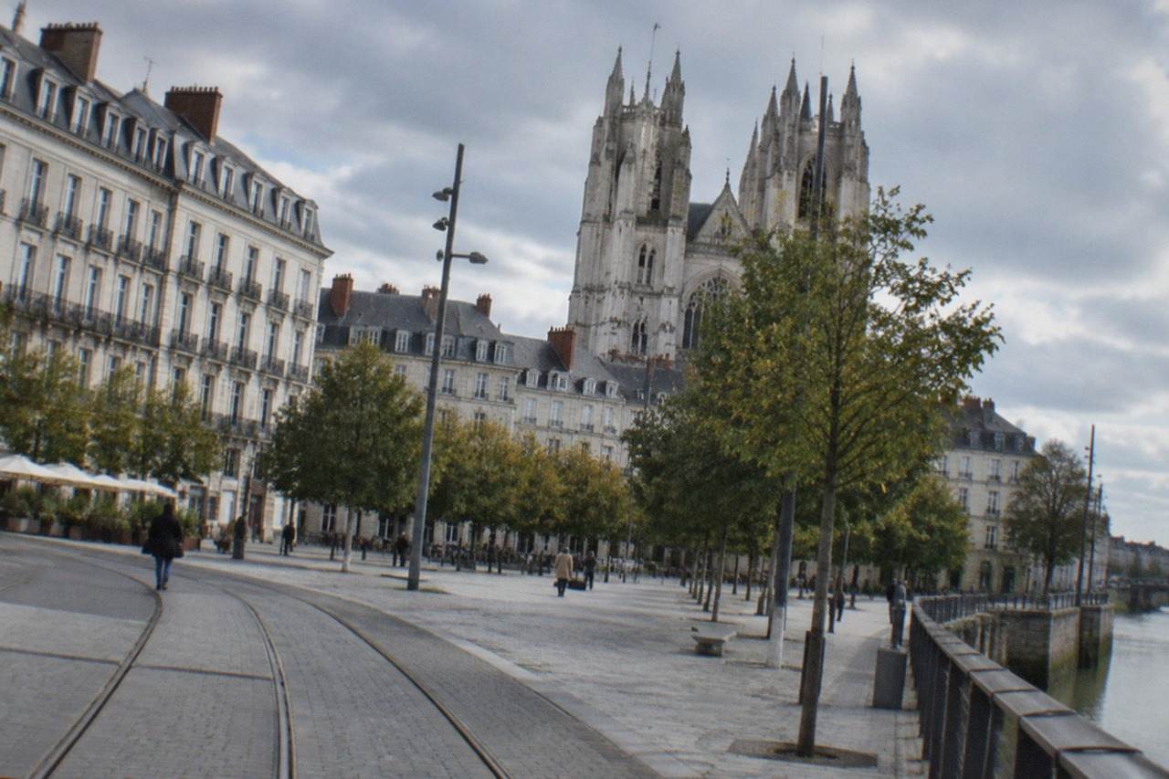 Tall gothic cathedral towers rising above a tiled square in central Nantes