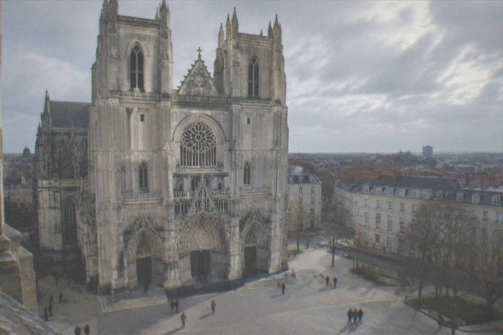 Visitors walking through a bright stone cathedral interior with high vaulted ceilings