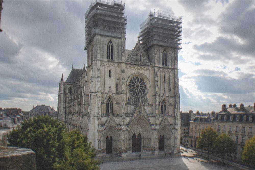 Scaffolding wrapped around the upper towers of a gothic cathedral under restoration