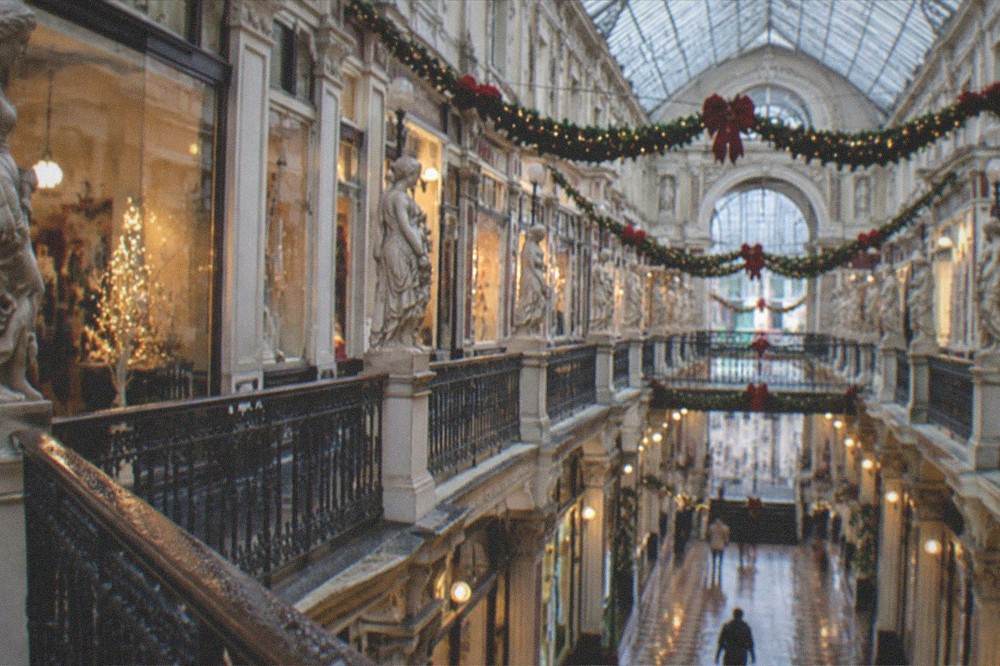 A covered arcade interior at Christmas time with festive garlands strung under a glass roof
