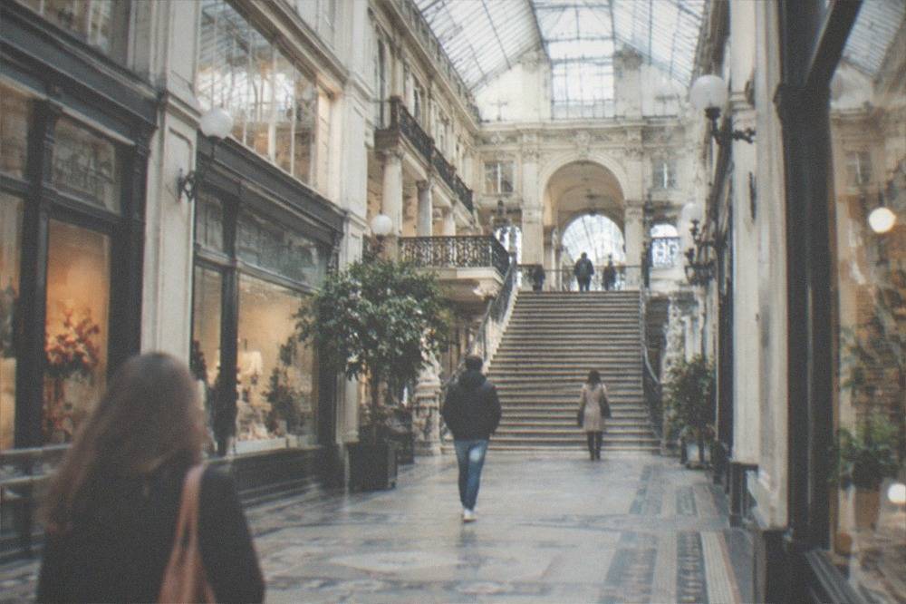 A covered 19th century shopping arcade with a glass roof, grand staircase and ornate shopfronts in Nantes