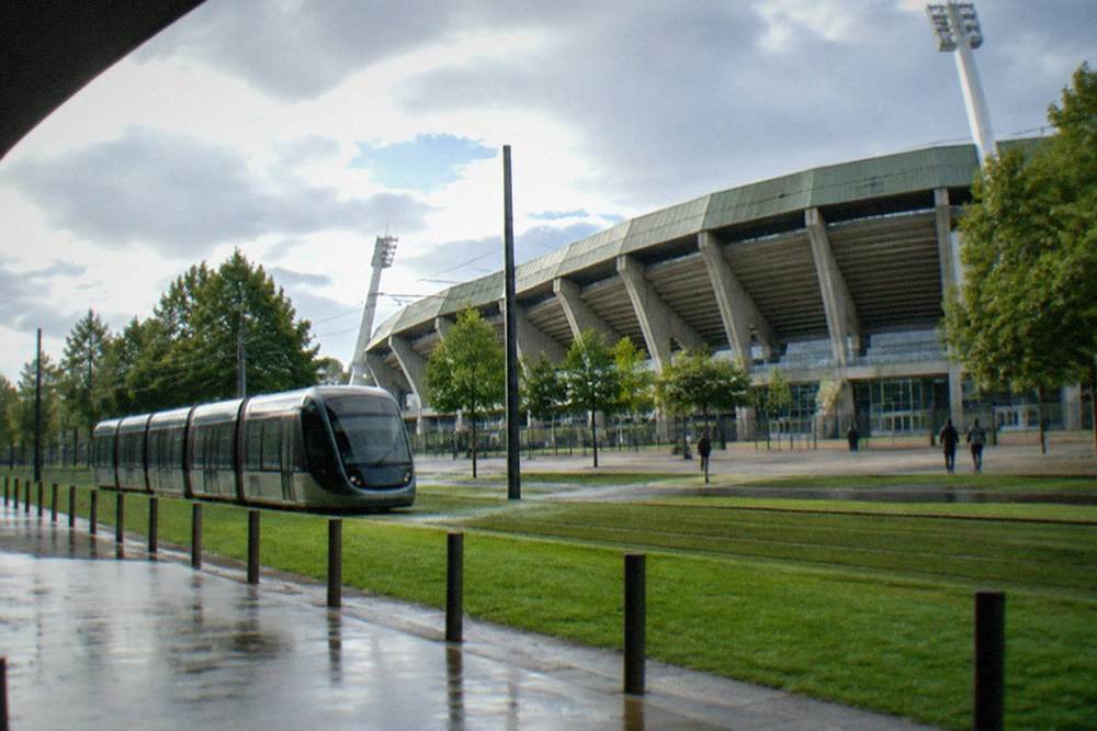 A modern tram travelling along a grass-covered track in a French city street