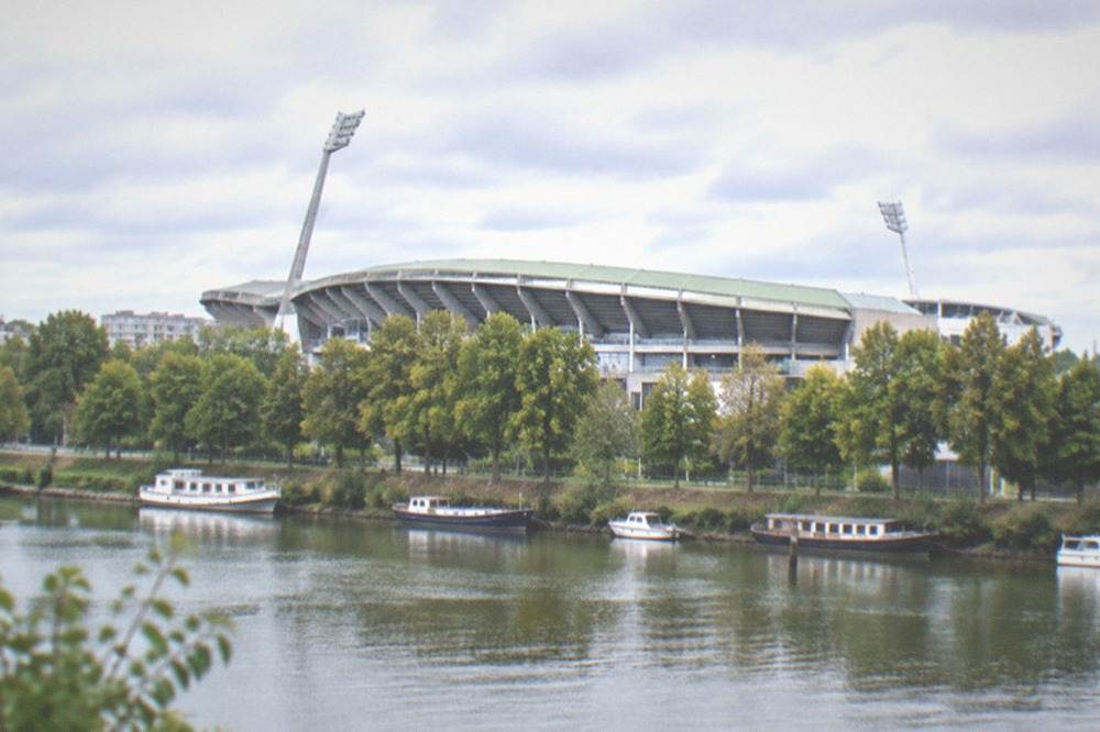 A tree-lined riverbank with small boats moored along calm water