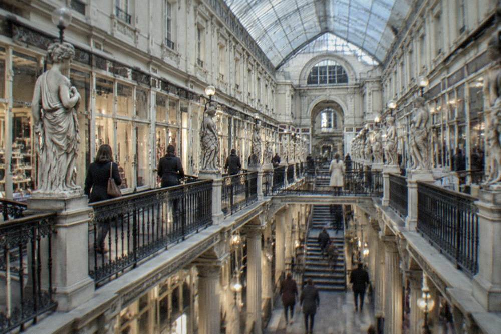 Shoppers walking through the lit galleries of the Passage Pommeraye in Nantes