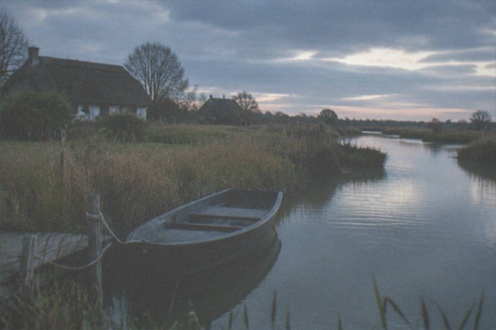 A small flat-bottomed boat moored among reeds on a narrow marsh channel