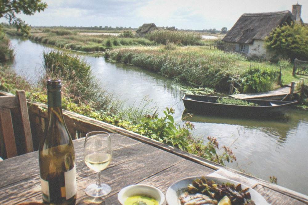 A rustic restaurant table set with a bottle of white wine and a butter sauce dish