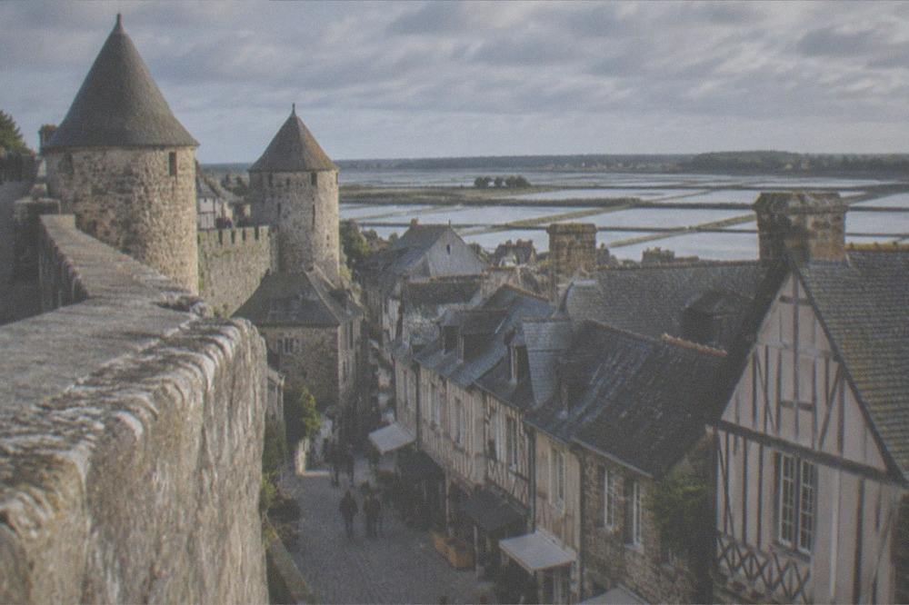 Medieval stone town walls above a street of small shops in Guerande