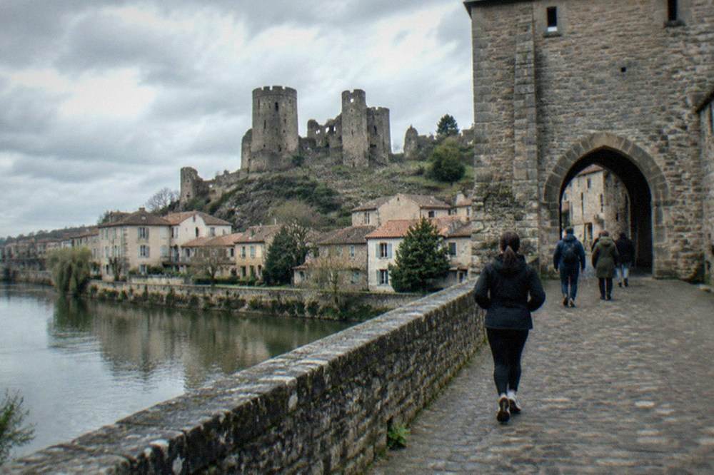 Visitors walking through the arched gateway of a medieval French château