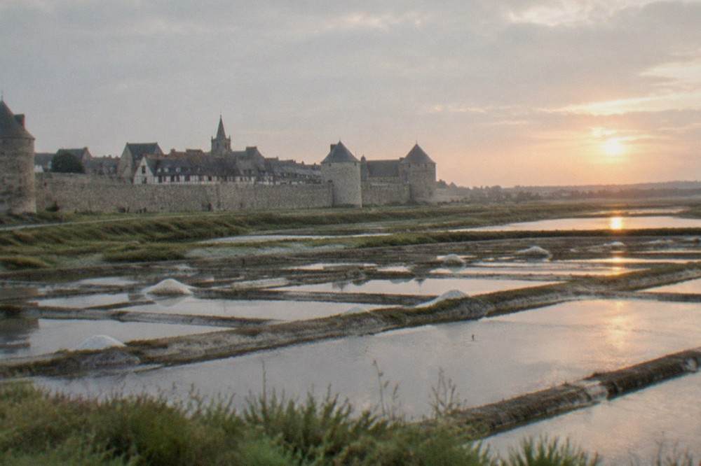 View across geometric salt pans toward a low horizon at sunset