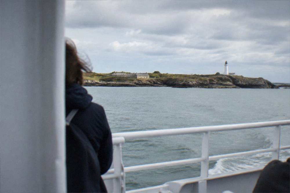 An open ferry deck mid-crossing with the island coastline low on the horizon ahead