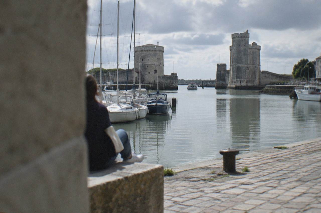 Fishing and pleasure boats mooured in an old harbour with stone towers guarding the narrow channel entrance