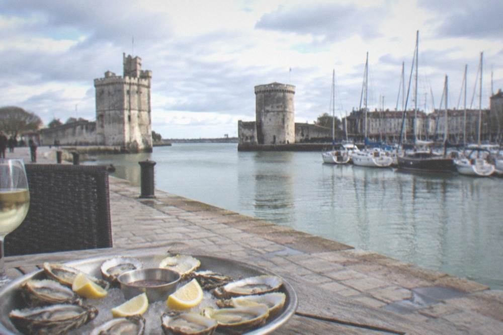 A platter of fresh oysters and lemon wedges on a quayside restaurant table