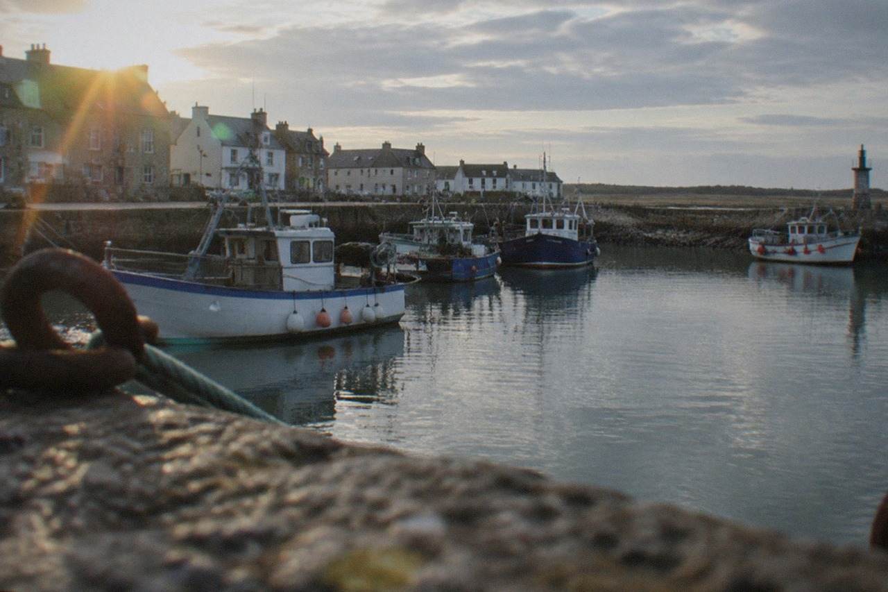 Fishing boats moored in the harbour at Le Croisic with stone harbour walls under a bright sky