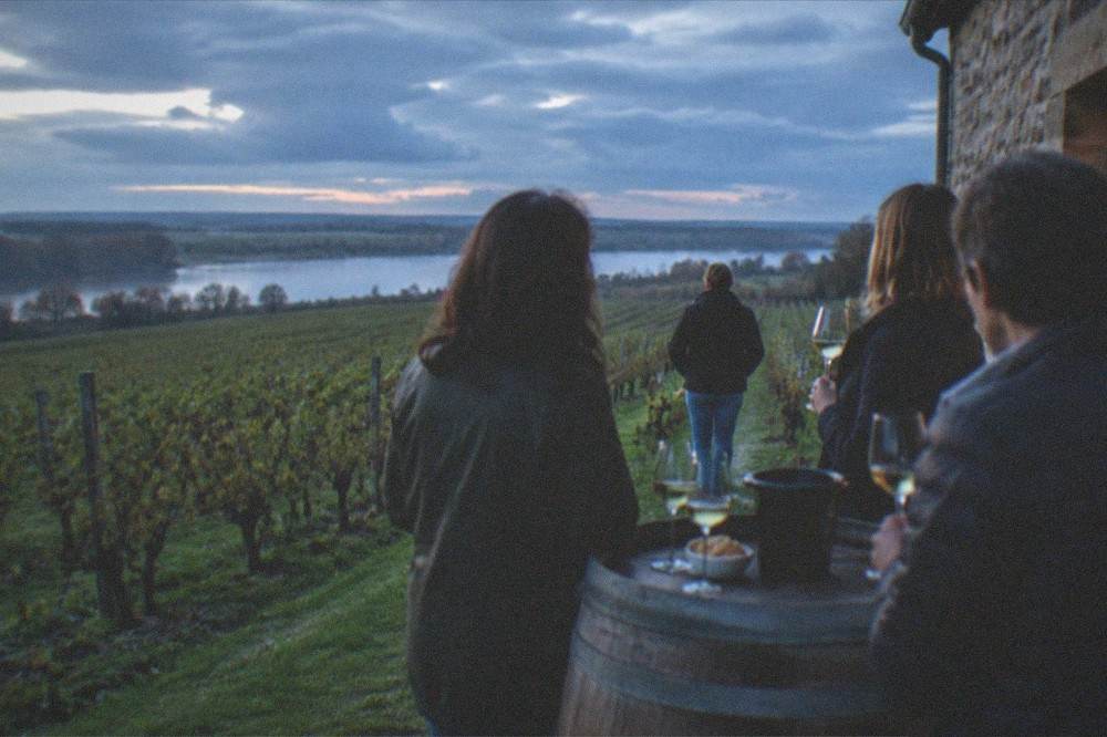 A small-group vineyard tasting with glasses of white wine on a barrel-top in a Muscadet cellar