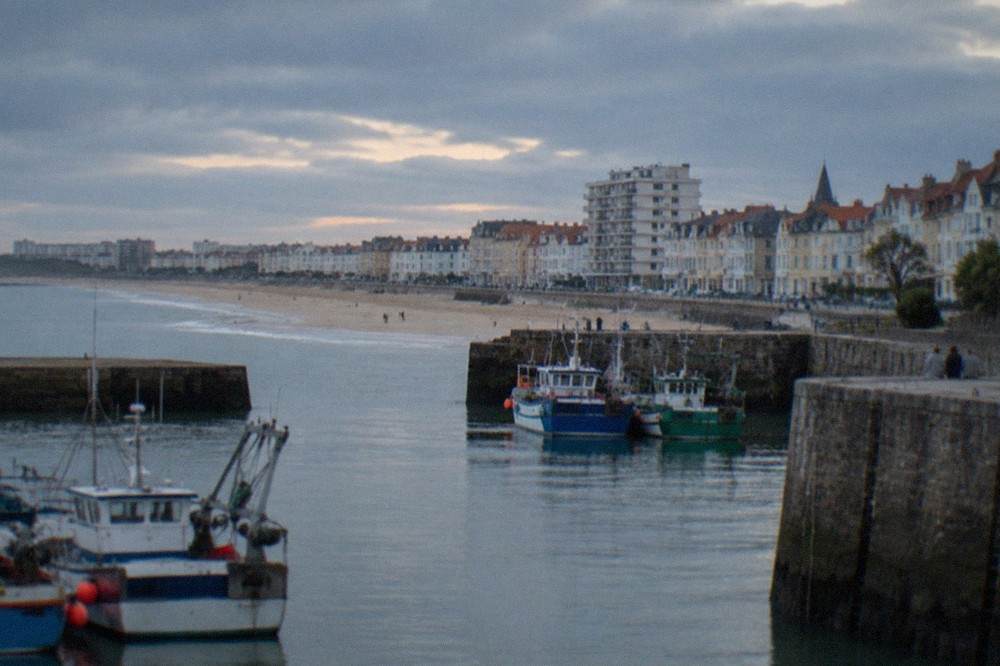 Fishing boats moored in a harbour with stone quays and gabled houses behind
