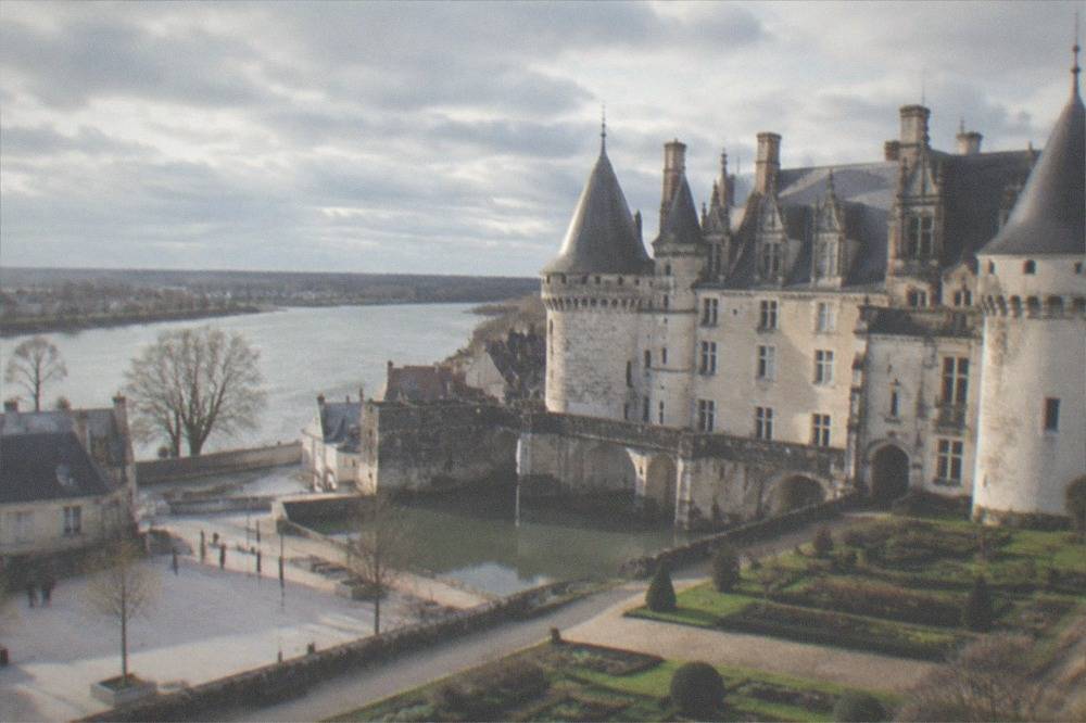 A fortified castle with towers and a moat beside a modern city square
