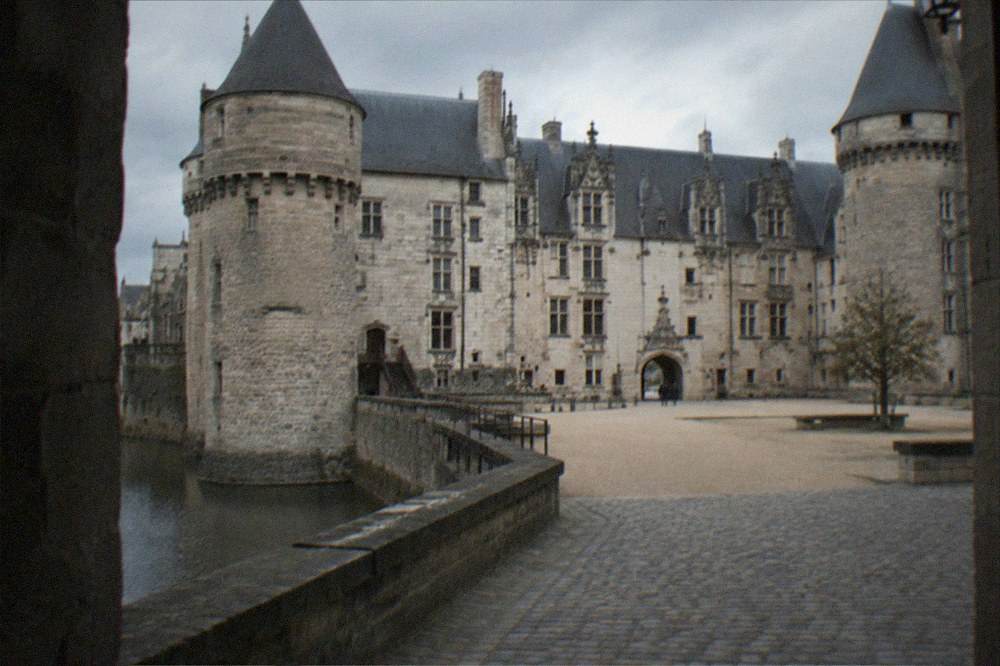 A quiet castle courtyard with stone walls and a gateway in morning light