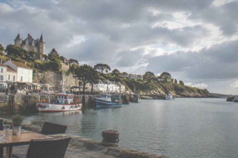 A table set outside a restaurant on a harbour quay, with fishing boats moored in the background