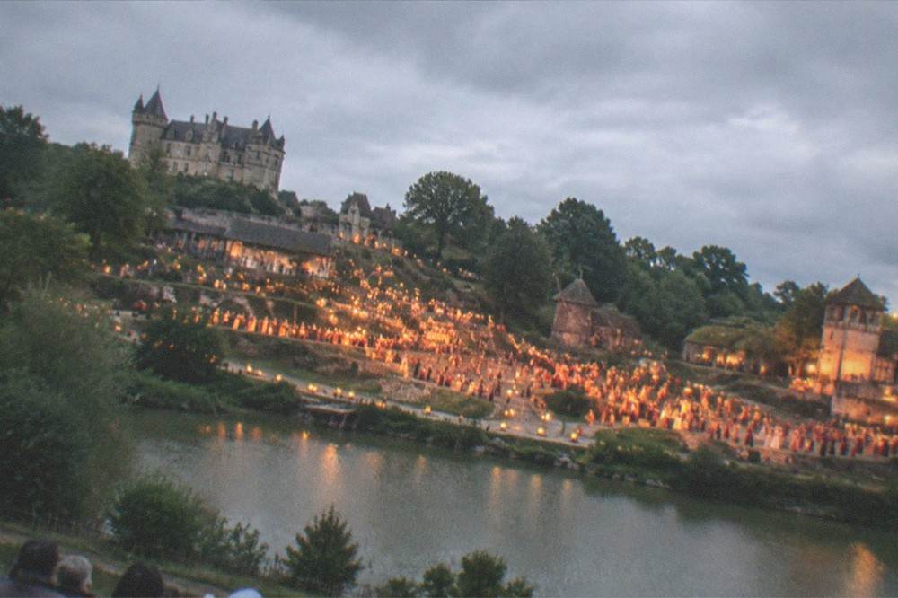 An illuminated night show with hundreds of performers and lanterns filling a hillside stage