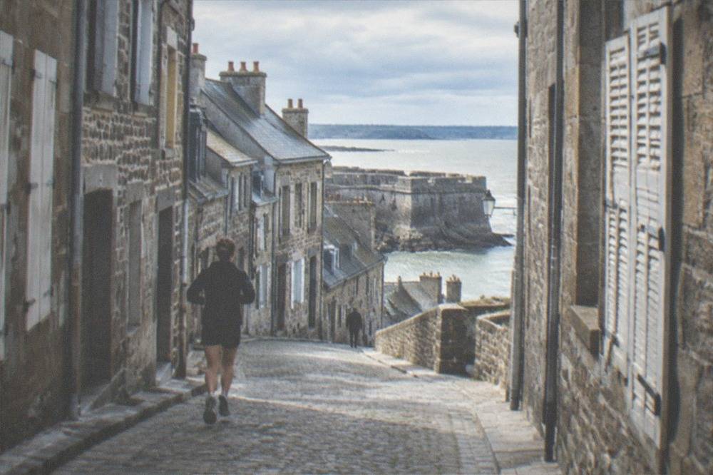 Narrow granite-paved lane between tall old town houses with shutters