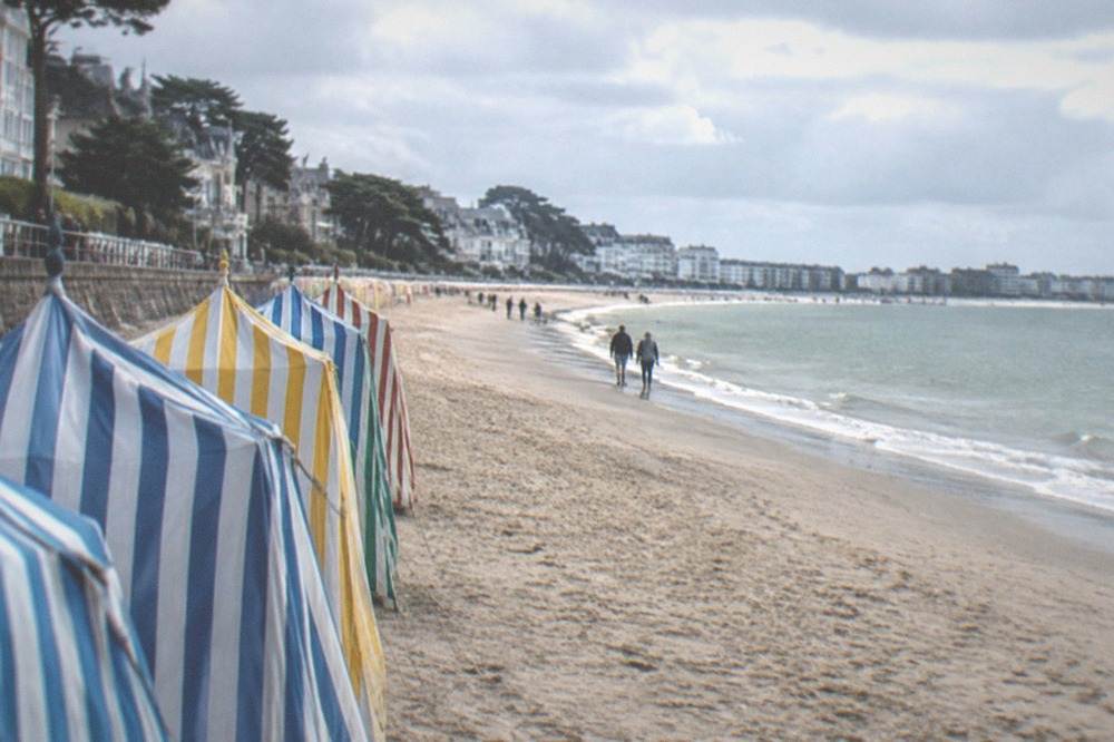 A long sandy beach at La Baule with colourful bathing tents along the promenade