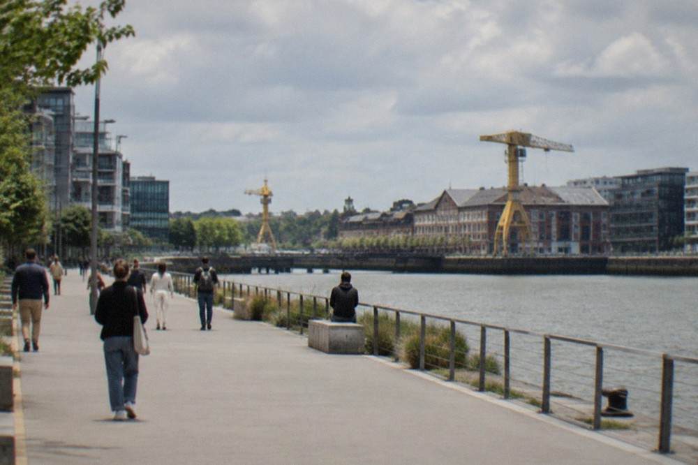 A smooth modern boulevard on the Ile de Nantes with wide pavement and people walking beside the Loire
