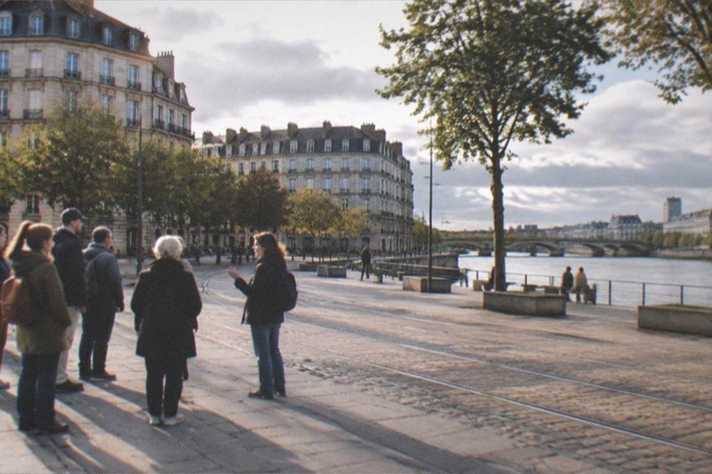 A small guided walking group pausing on a wide paved square in central Nantes