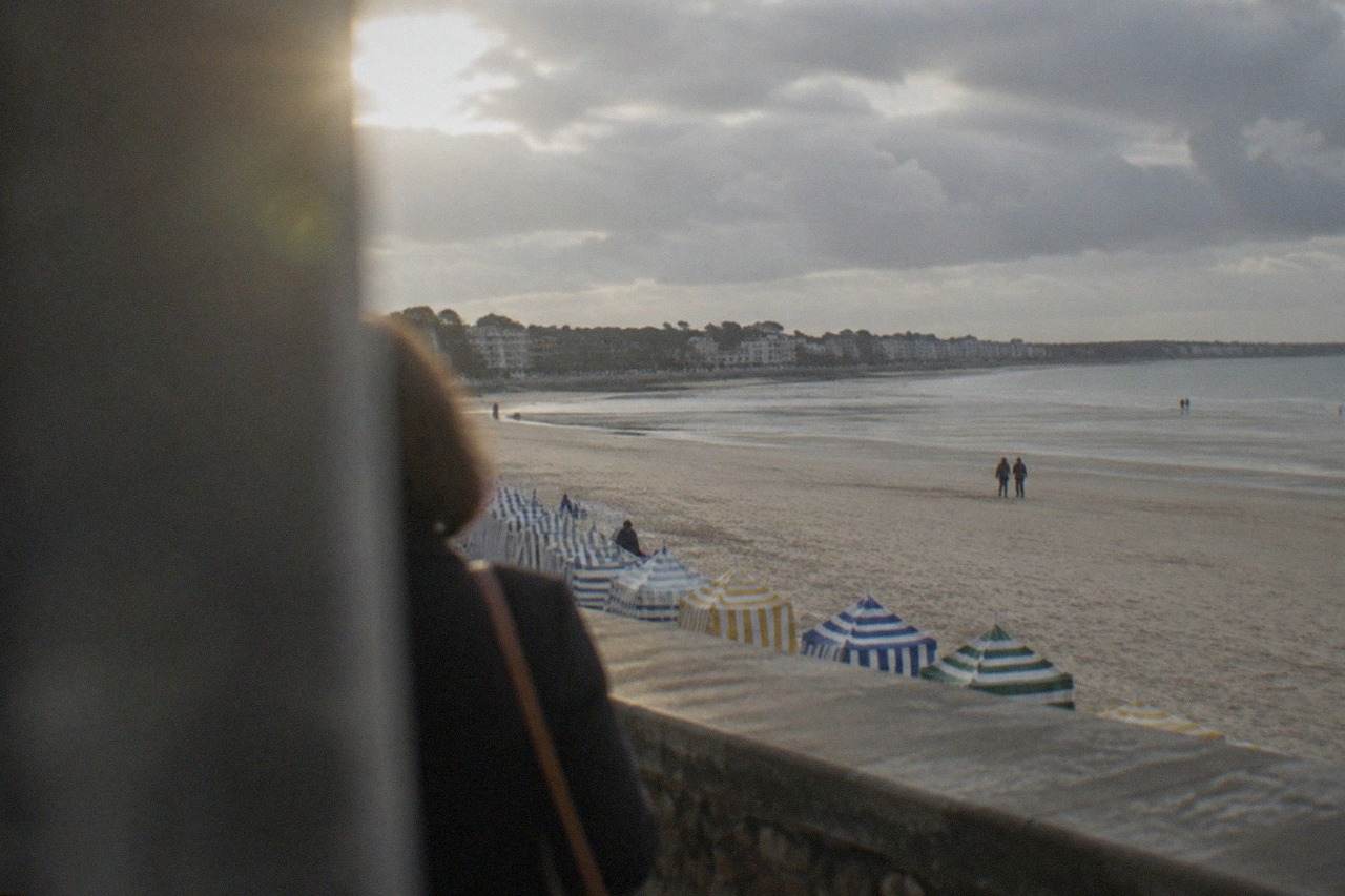 Wide sandy beach at low tide with colourful striped bathing tents along the promenade