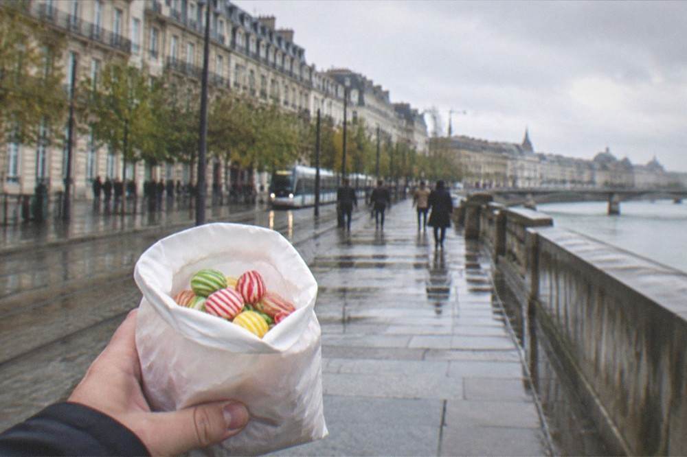 A souvenir paper bag filled with striped berlingot candies held in a hand on a Nantes street