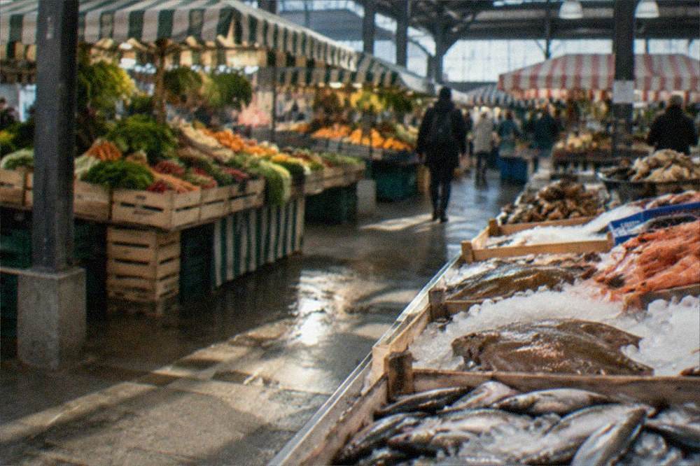 Open-air market stalls with fresh produce under striped awnings