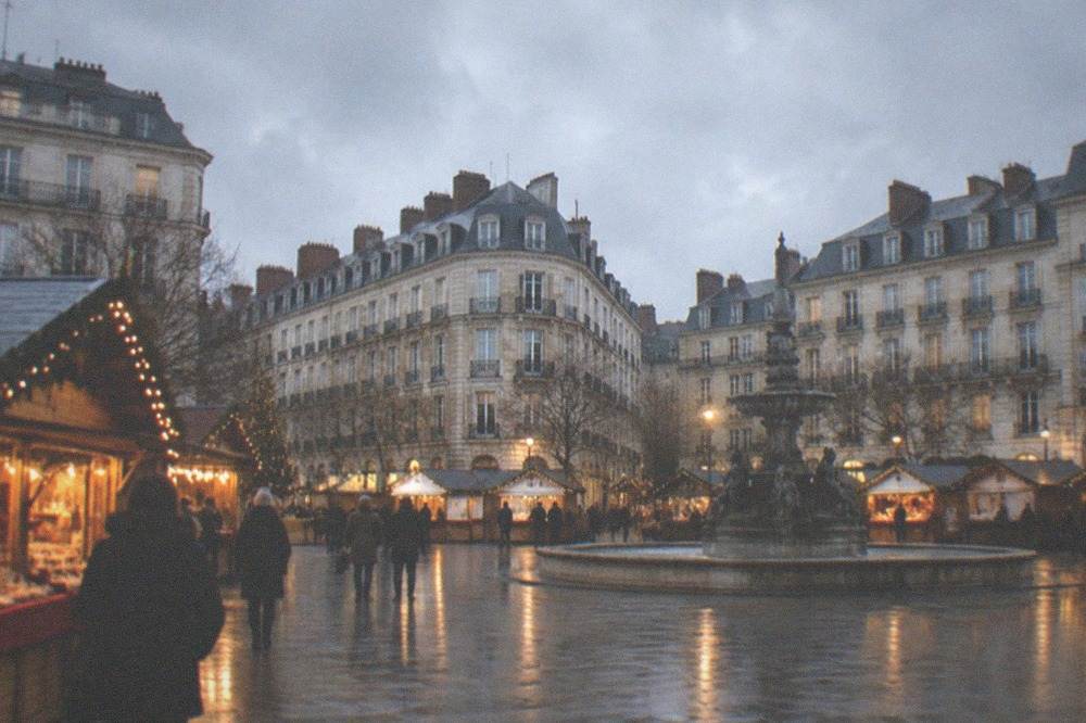 Festooned wooden chalets of the Nantes Christmas market lit up on Place Royale in the evening