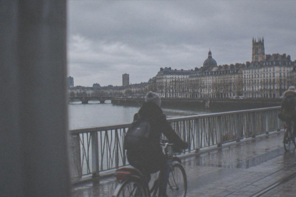 Cyclists crossing a bridge over the Loire with the Nantes skyline in low winter light