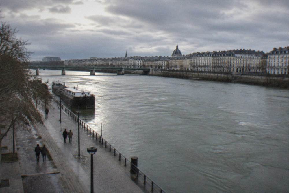 A high fast-flowing River Loire in Nantes seen from a quay with grey skies