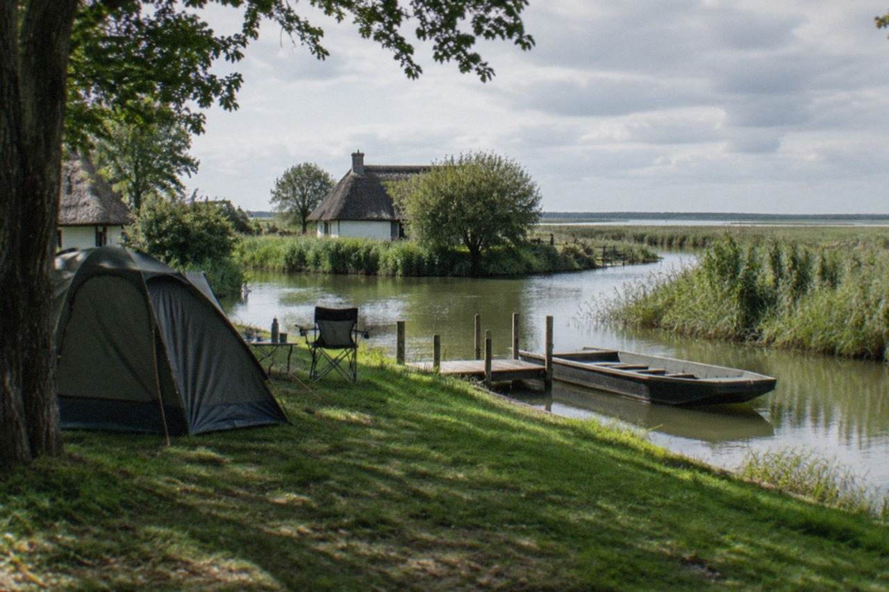 A family tent pitched on a grassy campsite with trees, morning light over the Loire in the distance