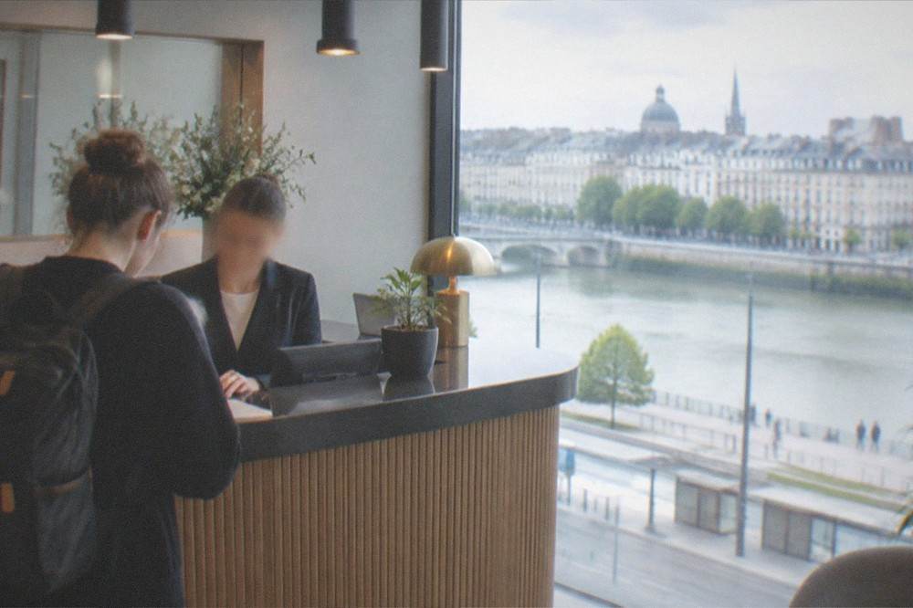 A hotel guest settling the city tourist tax at a reception desk in Nantes