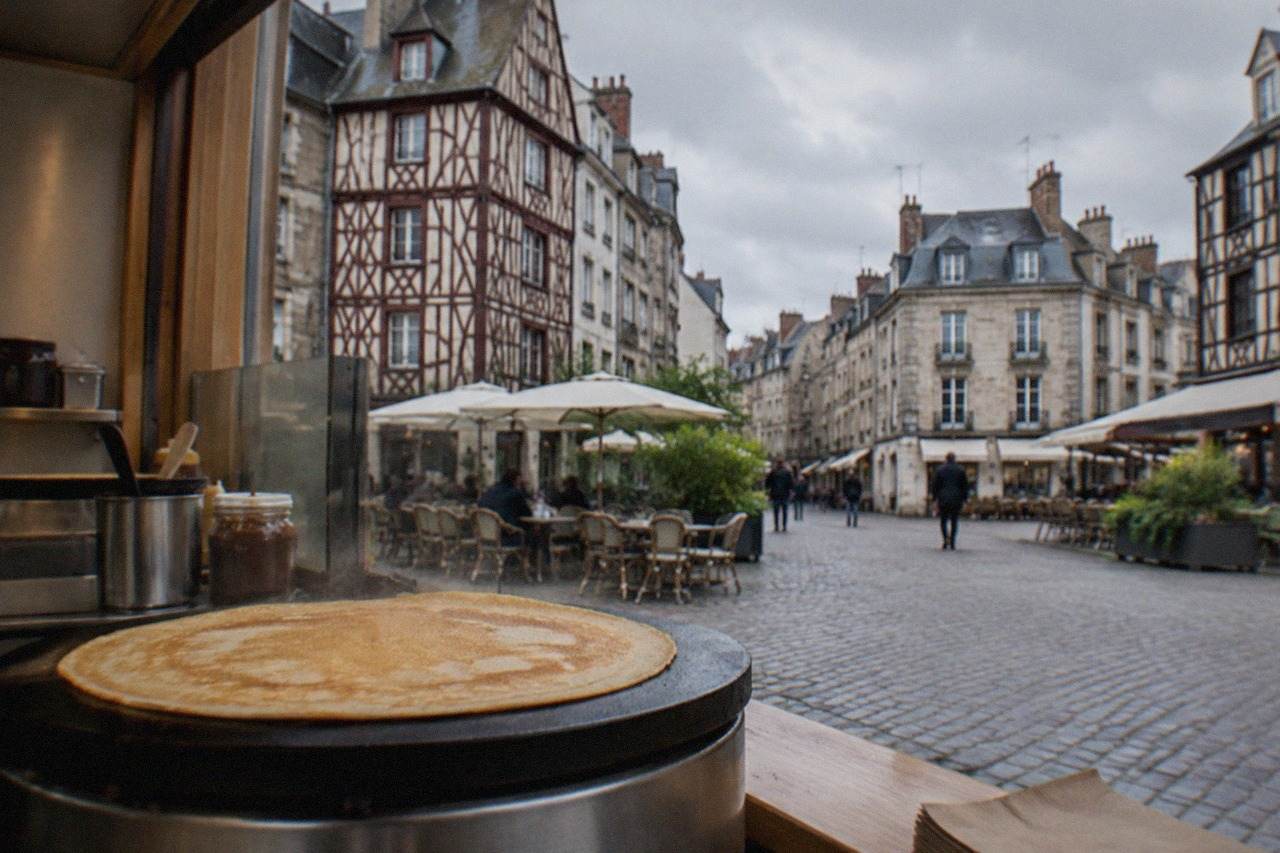 A round golden crepe cooking on a flat griddle inside a French creperie