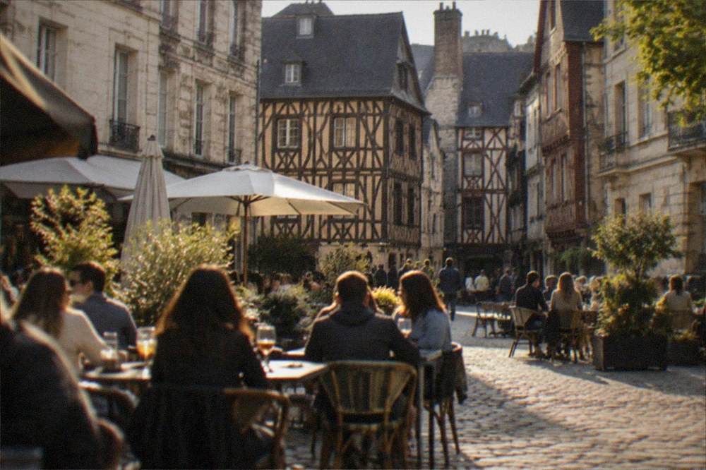 People eating at outdoor terrace tables on a sunny square in a French city