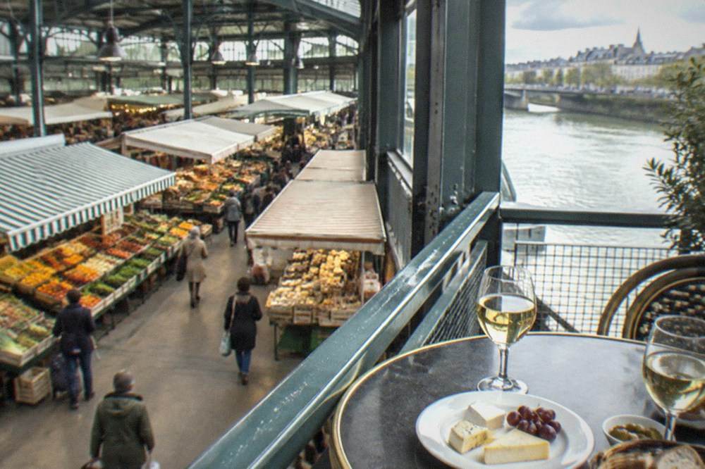 White wine glasses and a plate of cheese on a cafe table beside a river