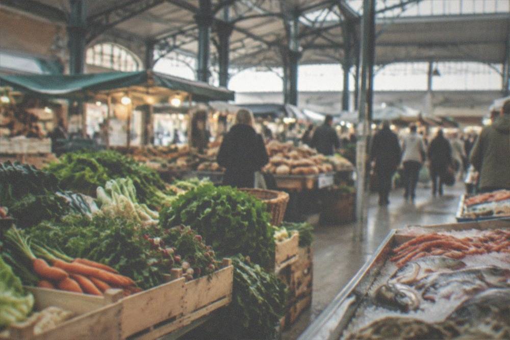 Market stalls with vegetables and bread in a busy covered market hall