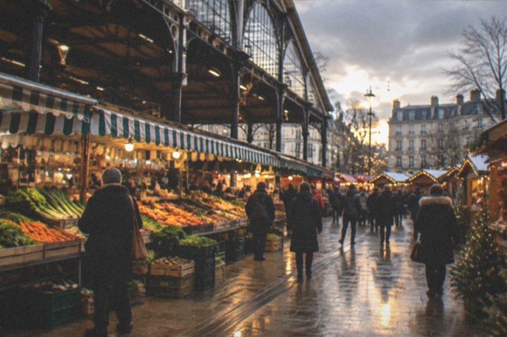 A Christmas market with wooden chalets and strings of lights on a city square at dusk