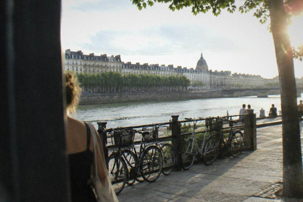 Bicycles parked against a railing beside a wide river on a bright summer day in Nantes