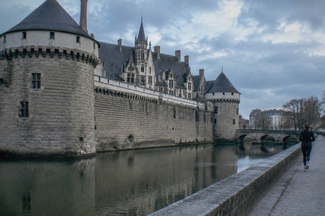 The stone ramparts and slate roofs of the Château des ducs de Bretagne in Nantes seen across the moat on a bright morning