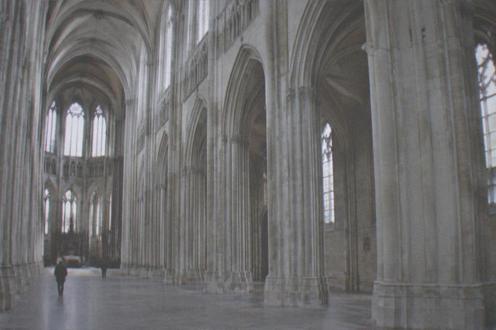 The wide stone nave of Nantes cathedral with tall columns and light falling from the clerestory windows onto the empty floor