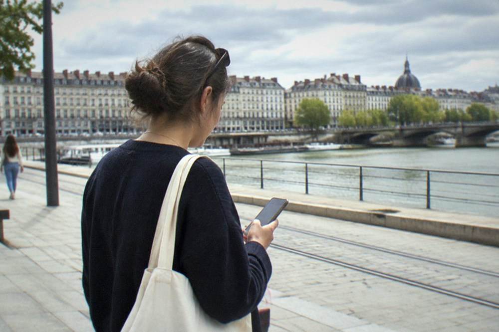 A traveller checking a phone map beside the Loire riverfront in Nantes
