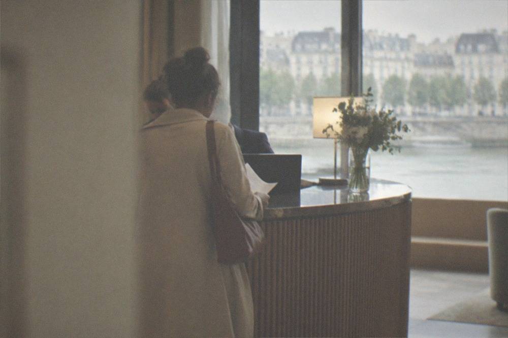A hotel reception desk in Nantes with a guest checking a paper bill