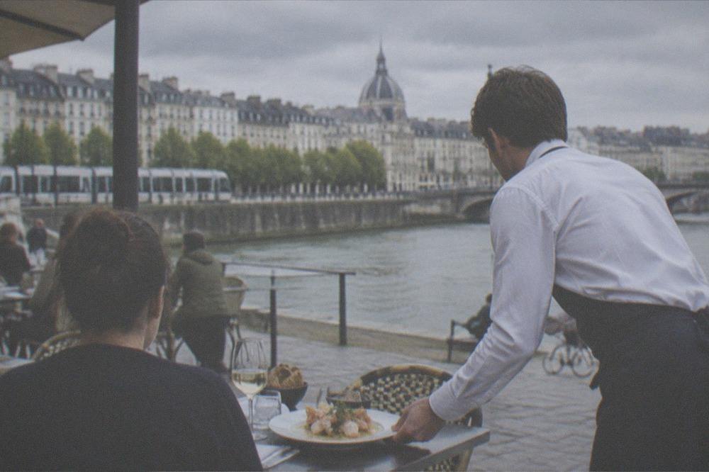 A waiter setting down a seafood dish with beurre blanc sauce on a restaurant table in Nantes